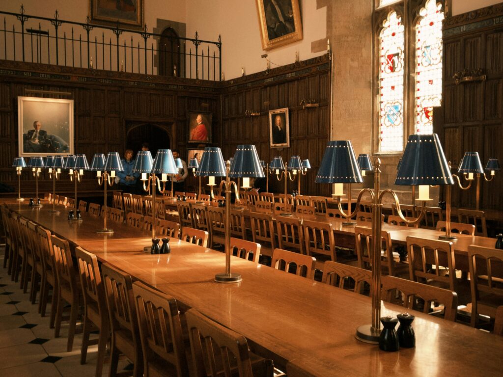 Elegant dining hall with wooden furniture and decorative lamps in Oxford, UK.