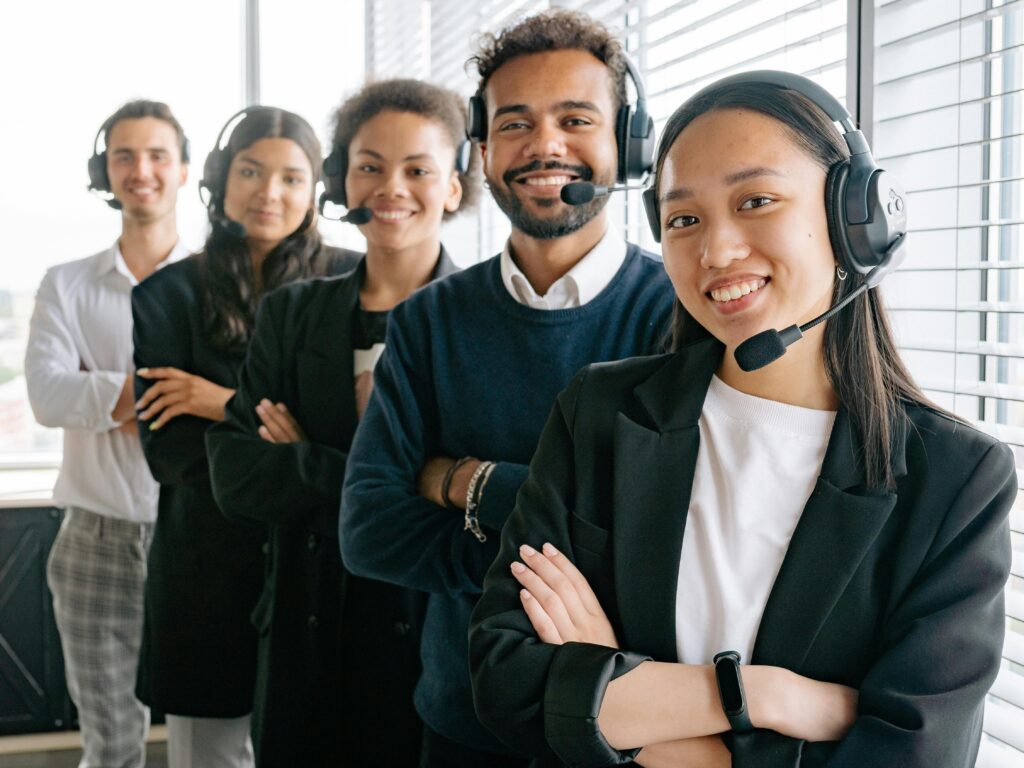 A diverse group of smiling call center agents in an office setting.